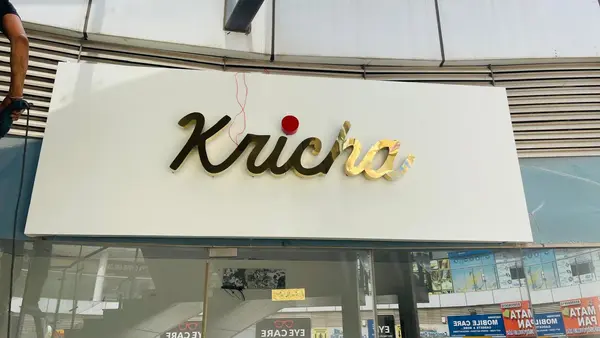 Kricha gold SS script sign during installation by Brandmaxx